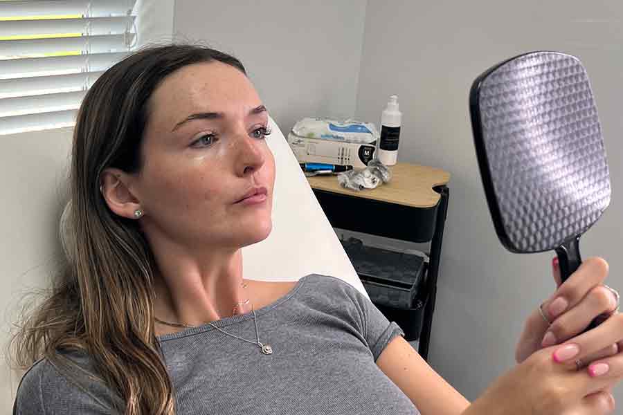 woman in beutician chair looking at herself in a mirror