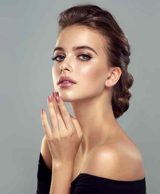 beautiful young woman with painted fingernails holding her hand up to her chin