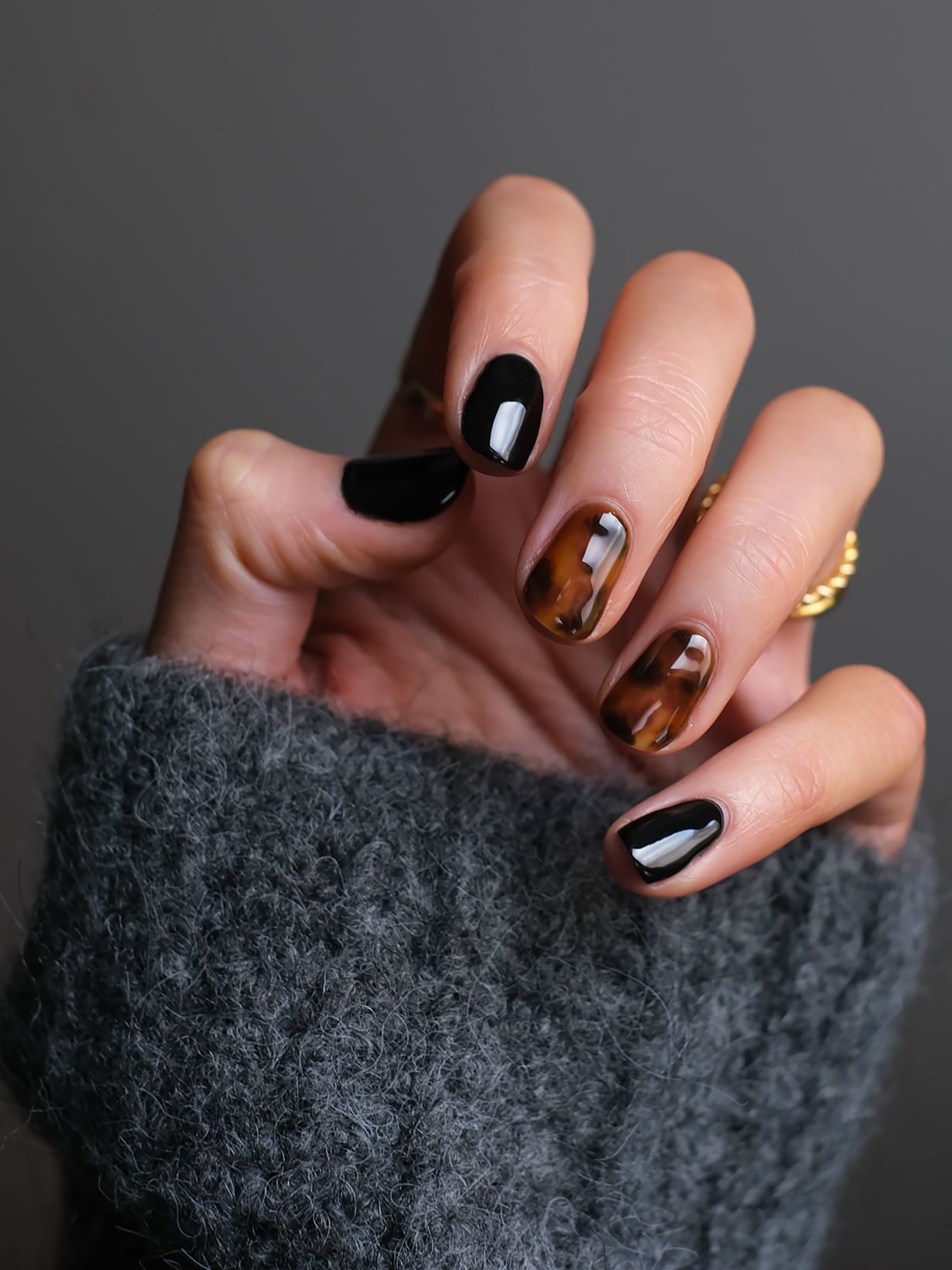 womans hand in a dark jumper with painted fingernails
